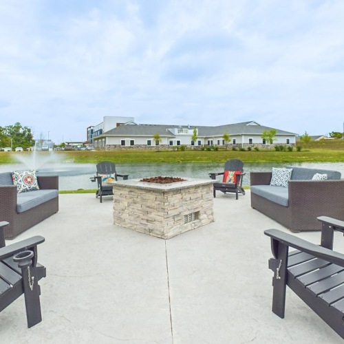 The essence of exceptional living in Allen County a fire pit with chairs and a pond
